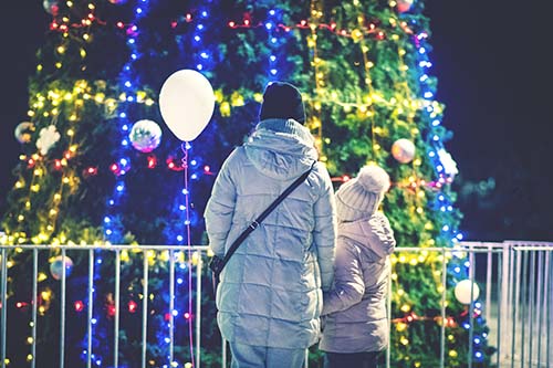 adult outside looking at holiday decorated tree