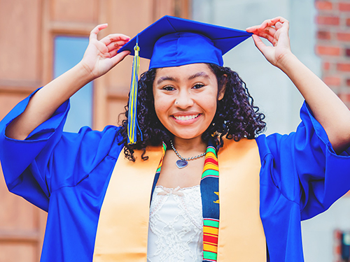 graduate with blue cap and gown with yellow stole