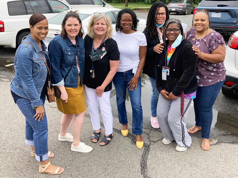 group of seven people standing in parking for photo