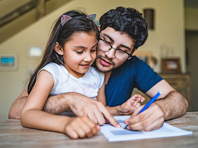 parent sitting with school age child doing homework