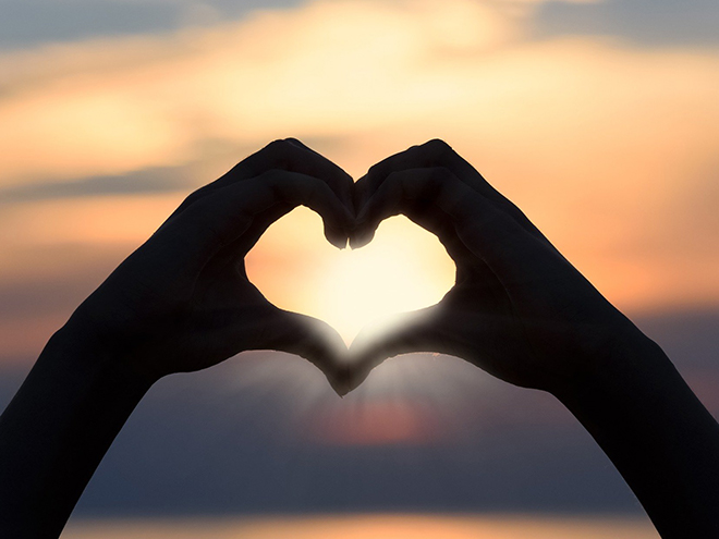 silhouette of hands with sun background form heart