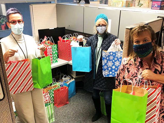 three people holding gift bags