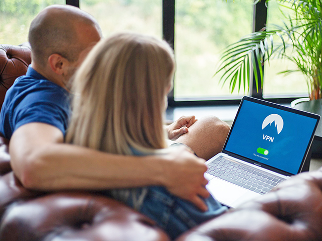 two adults sitting on sofa looking at laptop