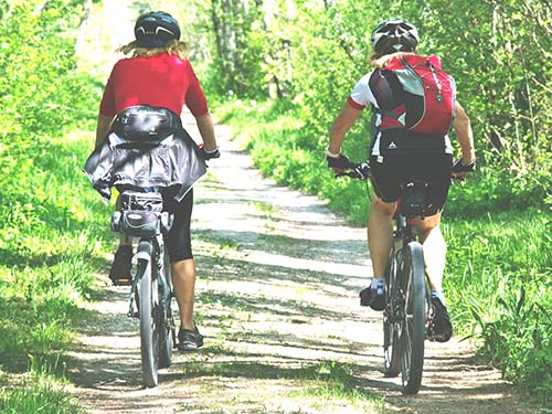 two people riding bicycles on path