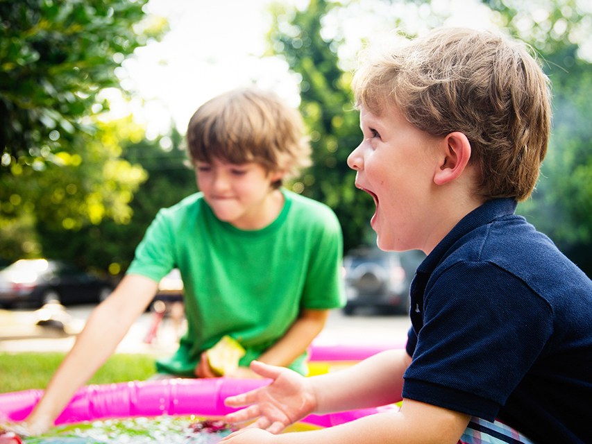 two young children playing water activity outside