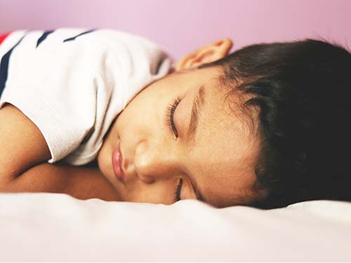 young child laying down with eyes closed