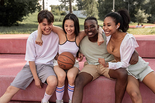 four teens seated with basketball