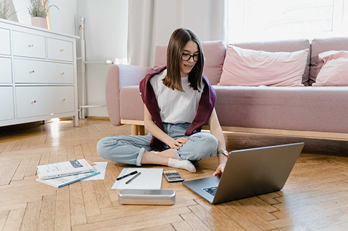 girl sitting cross-legged on floor with laptop