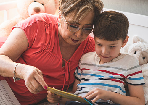 Older woman reading to child on bed