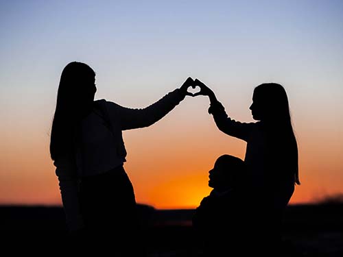 silhouette of two people with hands forming a heart and a young child sitting below