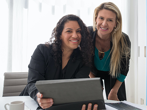 Two women smiling with laptop