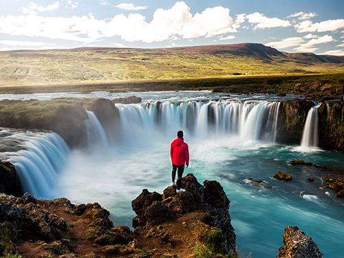 man standing at waterfall