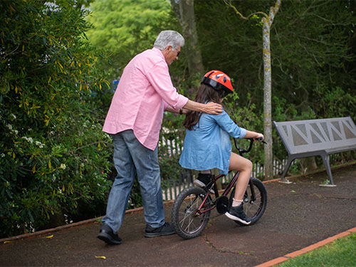 older man helping girl ride bike