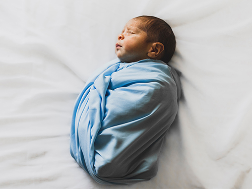 sleeping baby swaddled in blue