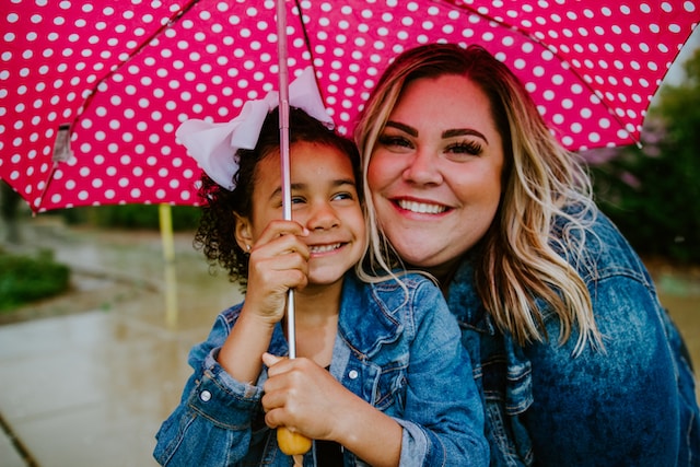 woman and girl smiling under umbrella