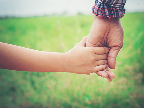 adult and child holding hands outside