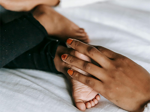 adult hand holding baby's foot