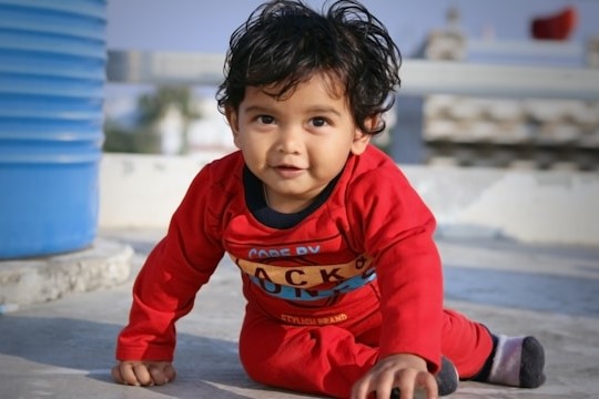 boy in red and blue sweater sitting on the floor
