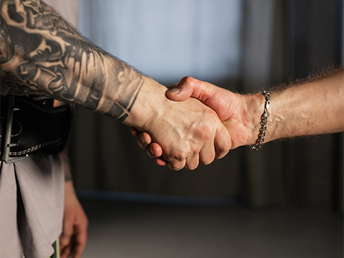 man with tattooed arm shaking hands