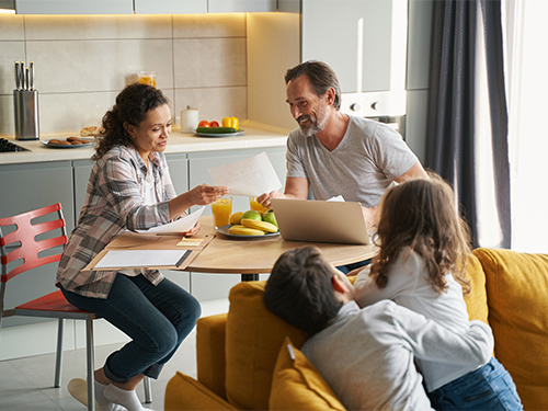 woman and man talking at kitchen table while children watch