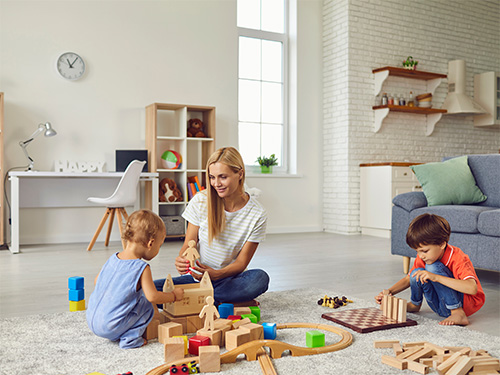  woman playing with two small children on floor
