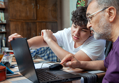 boy with older man using laptop