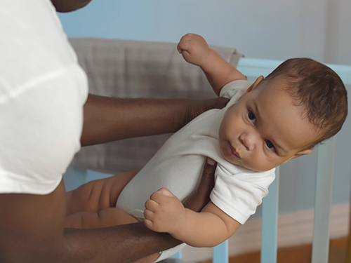 dad holding baby by crib