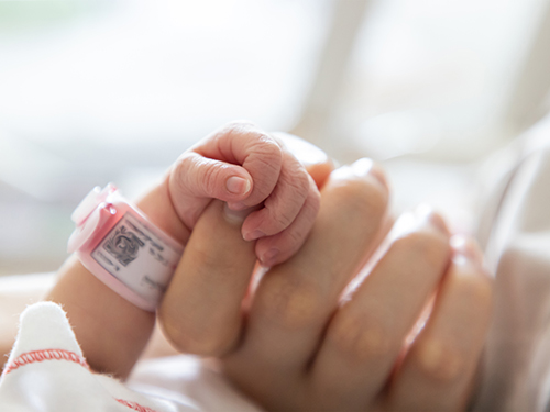 hand holding baby wearing hospital bracelet