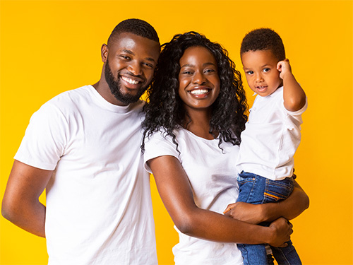 man and woman holding child with yellow background