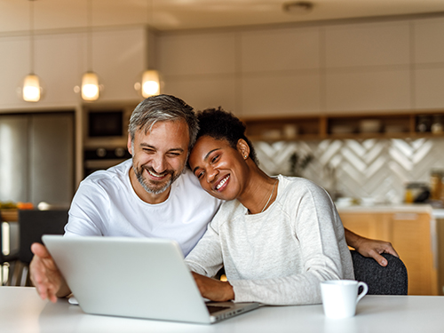 man and woman smiling at laptop