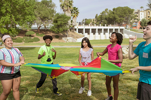group of tweens playing outside with parachute
