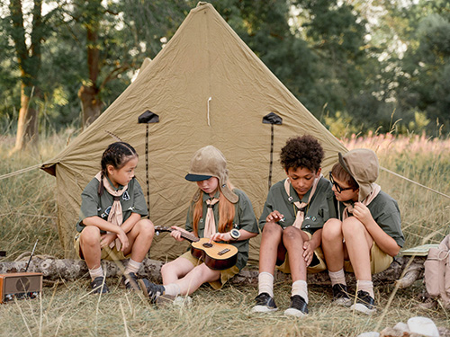 group of boy scouts sitting in front of tent