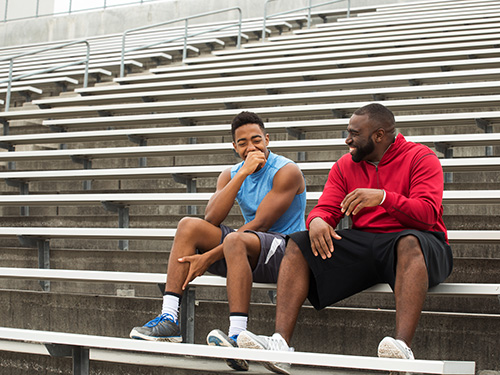 teen boy with man laughing on bleachers