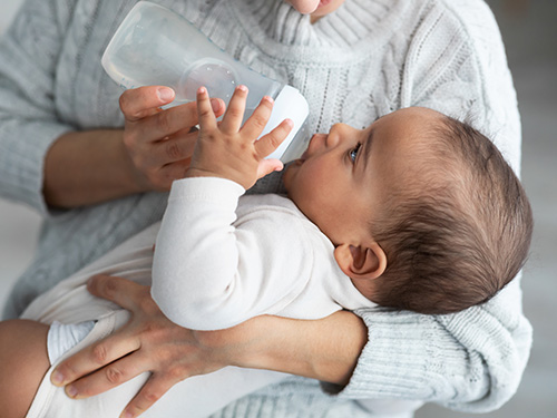 woman feeding baby with bottle