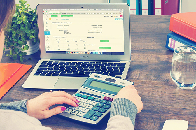 person using calculator and laptop computer