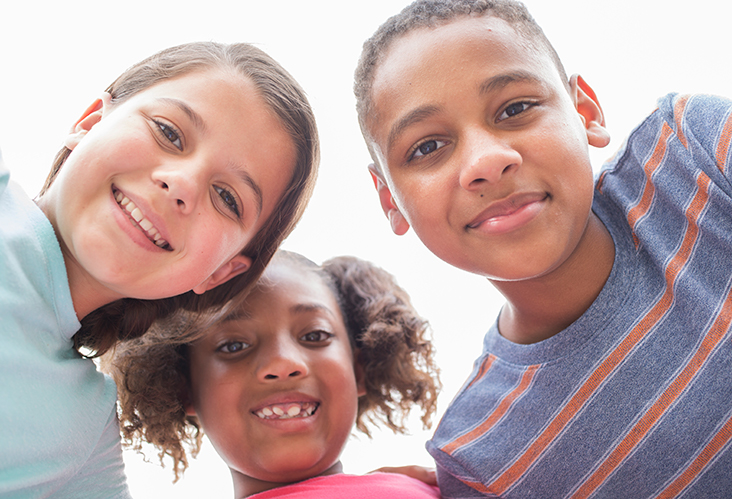 three children standing close looking down