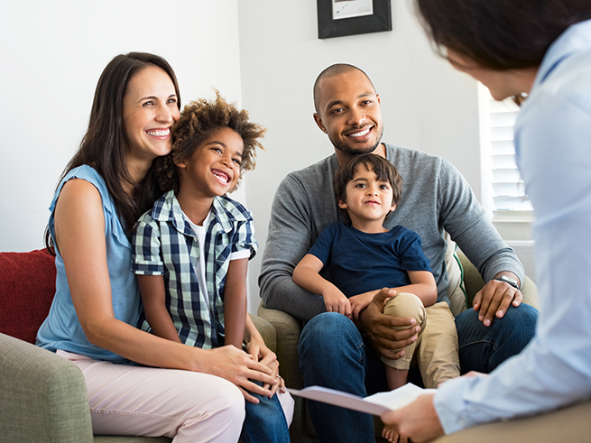 two adults each holding a child and talking to another adult