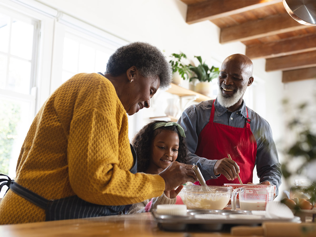 older man and woman cooking with child