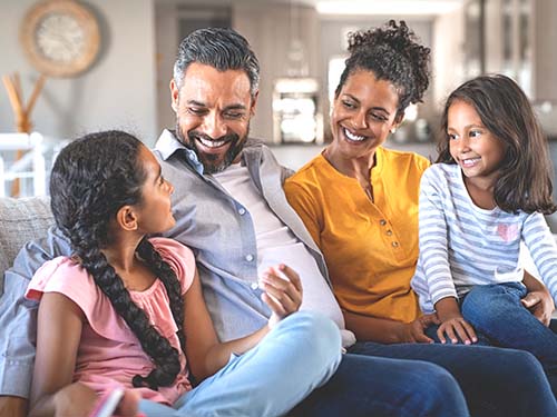 two adults sitting on sofa in between two children