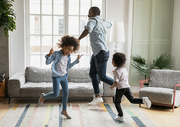 father dancing with two children in living room