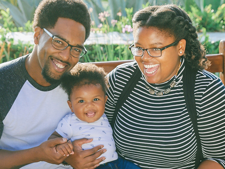 father and mother holding baby - all smiling