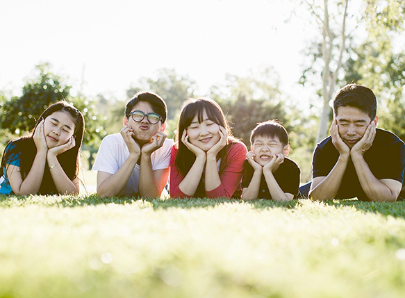 two parents and three children outside making facial expressions