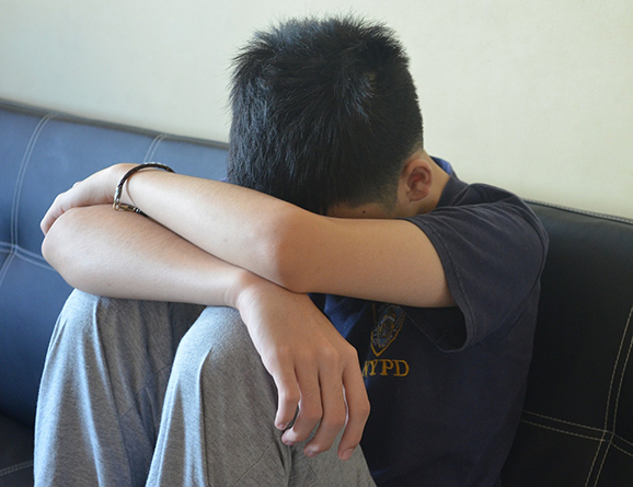 teen sitting covering face