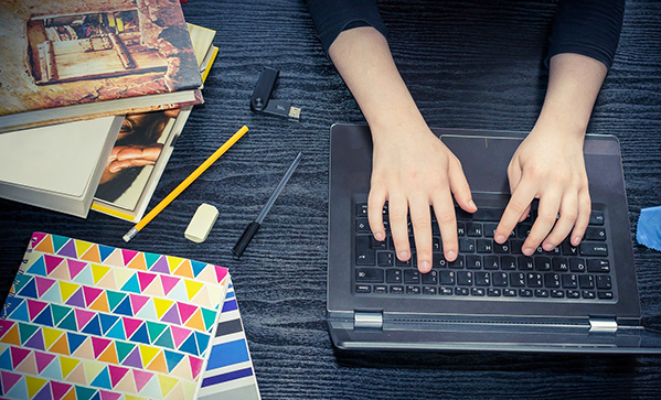 typing on laptop books pencils