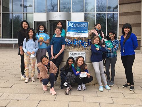 girl scout troop 50093 with pinwheel garden in front of Pennino Building