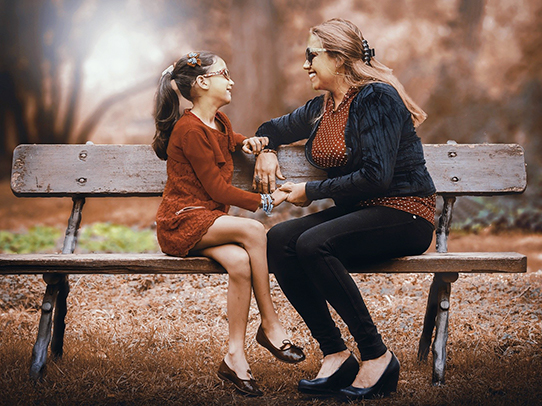 adult and child sitting on bench and talking