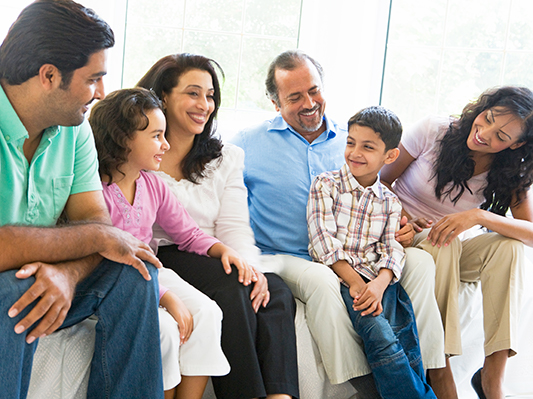 family of four adults and two children sitting together