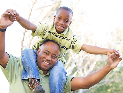 smiling child sitting on father's shoulder