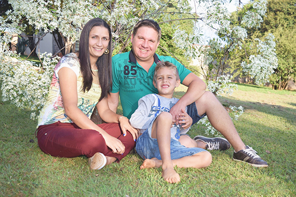 two adults and child outside sitting on grass