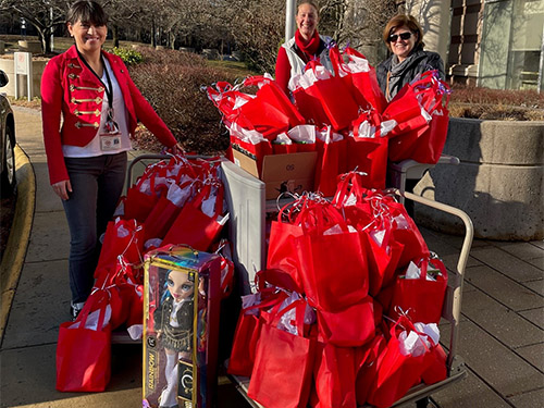 three people standing with red gift bags